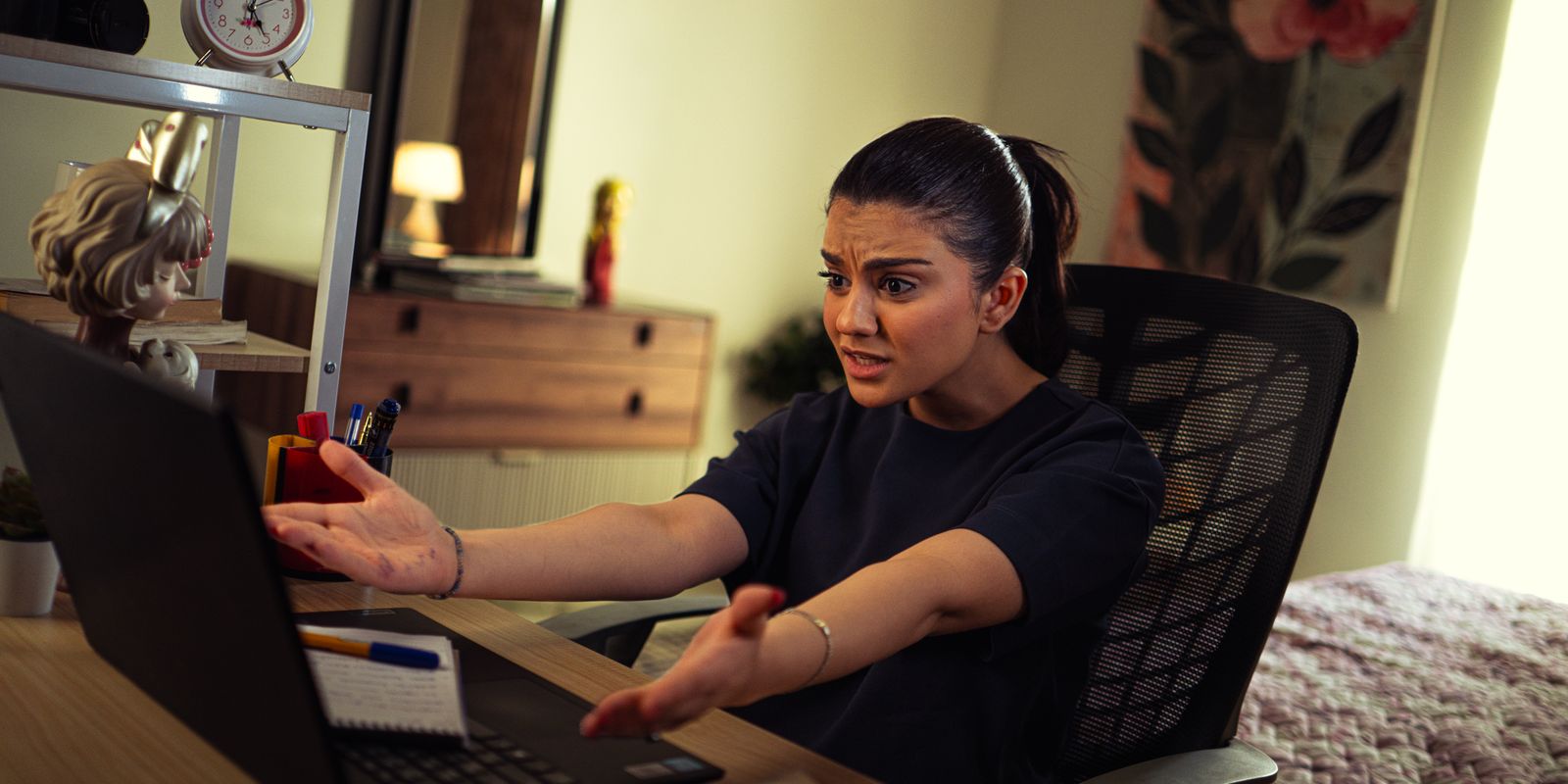 امرأة تجلس أمام حاسوب محمول وتبدو مترددة أثناء العمل في مشهد يعبر عن التسويف