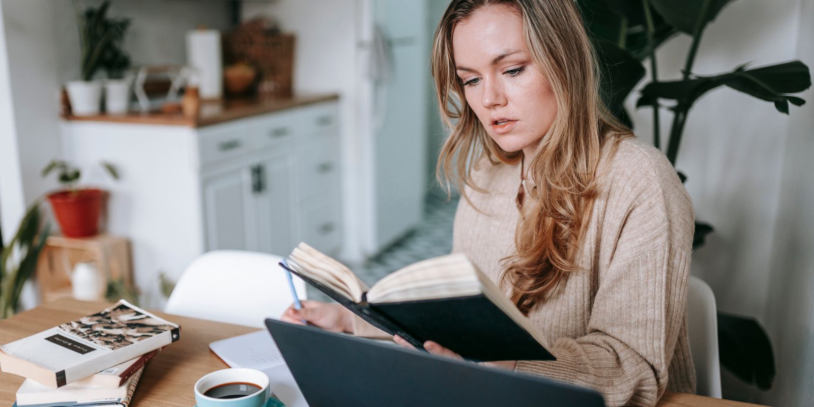 امرأة تدوّن ملاحظات في دفتر بجانب حاسوب، في صورة توضيحية لموضوع تكوين العادات اليومية