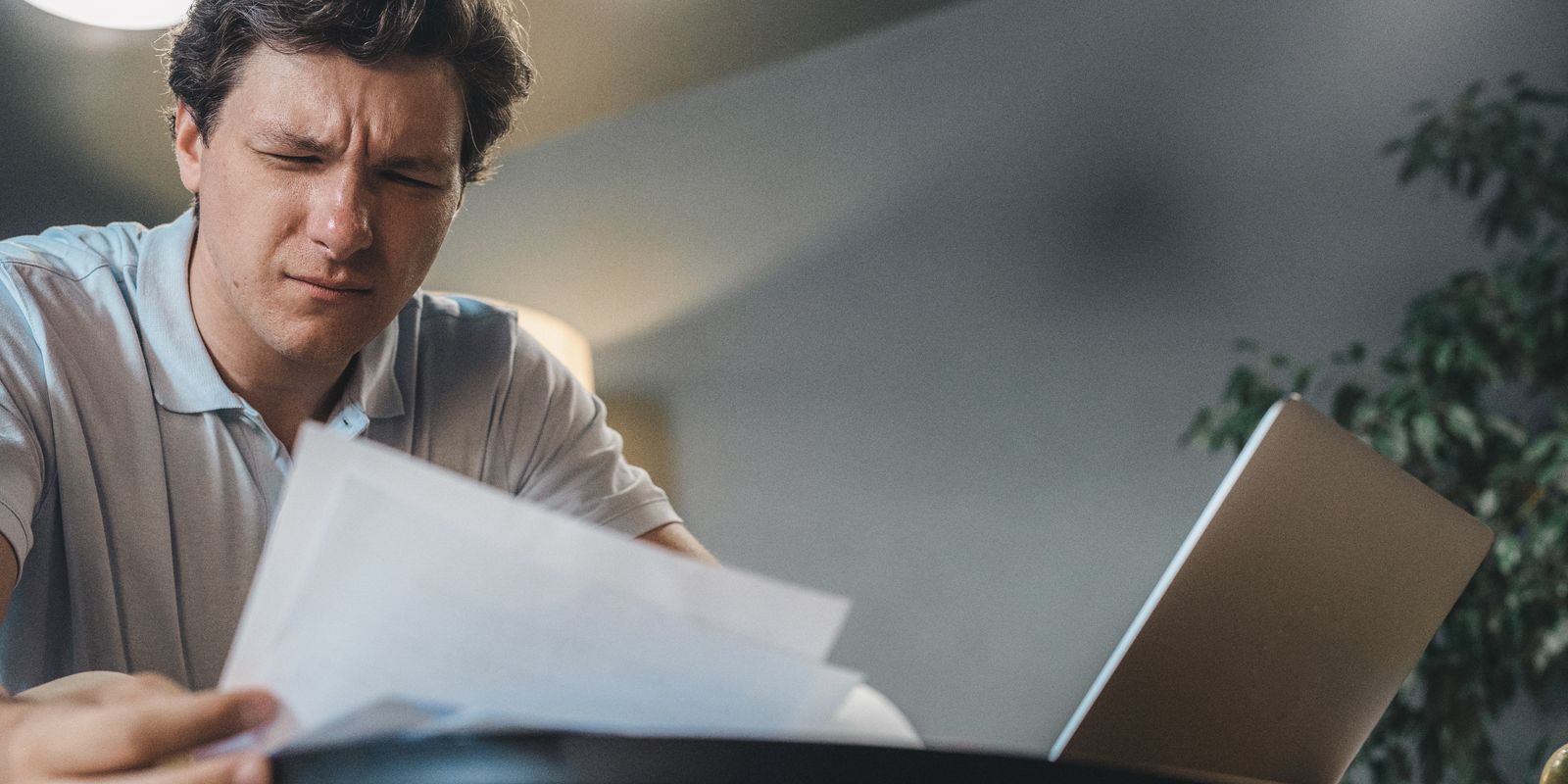 رجل يراجع مستندات وأوراقًا أمام حاسوب في مكتب هادئ